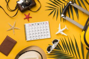 flat lay travel essentials with calendar sunglasses