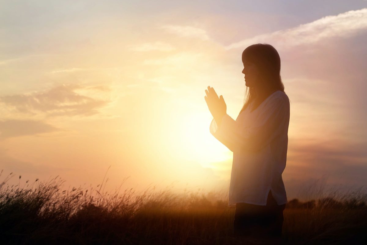 Mulher orando ao por do sol