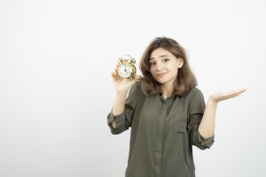 foto da garota da manha segurando o despertador sobre parede branca foto de alta qualidade