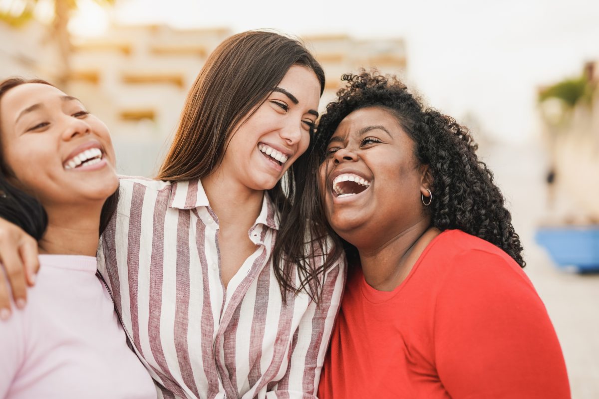 meninas multirraciais rindo juntas na cidade enquanto se abracam jovens mulheres latinas ao ar livre 1