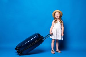 retrato de corpo inteiro de uma linda garotinha com bagagem isolada na parede azul passageiros que viajam para o exterior em escapadelas de fins de semana conceito de viagem de voo aereo 1